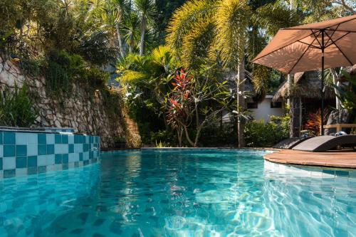 a swimming pool with an umbrella and a resort at Village Vibes Lombok in Kuta Lombok