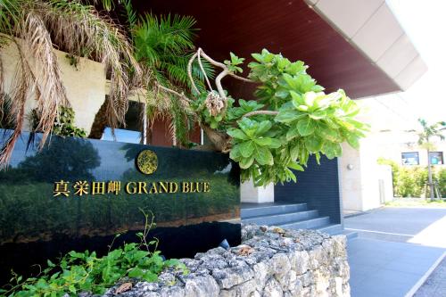 a sign in front of a building with plants at Maedamisaki Grand Blue 103 in Onna