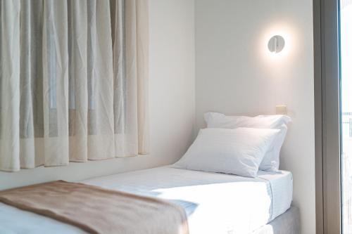 a bedroom with a bed with white sheets and a window at Costa Mare in Paralia Vrachou