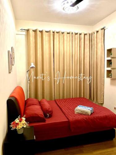 a bed with red pillows in front of a curtain at Marit's Homestay Sandakan in Sandakan