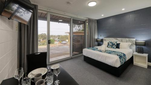 a bedroom with a bed and a large window at Hilltop Motel in Broken Hill