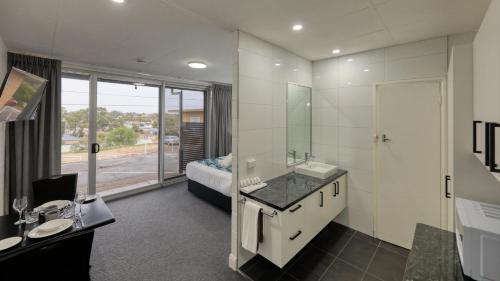 a bathroom with a sink and a mirror and a bed at Hilltop Motel in Broken Hill