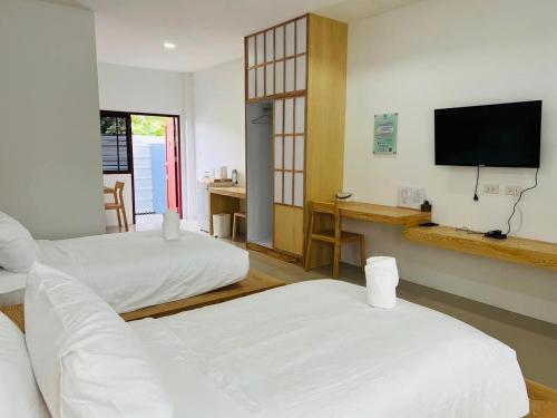 a hotel room with two beds and a flat screen tv at สราญรัตน์รีสอร์ท in Ban Noen Makok