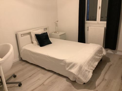 a bedroom with a white bed with a black pillow on it at Maison proche Avignon 2 chambres in Les Angles Gard