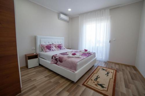 a white bedroom with a bed and a window at L&I Villa in Ulcinj