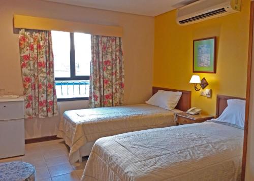a hotel room with two beds and a window at Hotel Bristol Asuncion in Asuncion