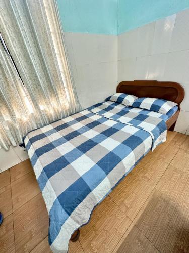 un letto con coperta a scacchi blu e bianca di BB Tài Thịnh a Quang Ngai