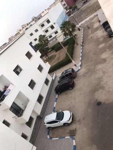 une voiture blanche garée à côté d'un bâtiment blanc dans l'établissement Résidence Talhaoui, à Saïdia