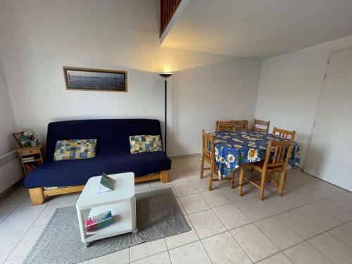 un salon avec un canapé bleu et une table dans l'établissement Maison de Vacances 8 Pers à 300m Plage avec Terrasse et Parking, Saint-Jean-de-Monts - FR-1-224C-272, à Saint-Jean-de-Monts
