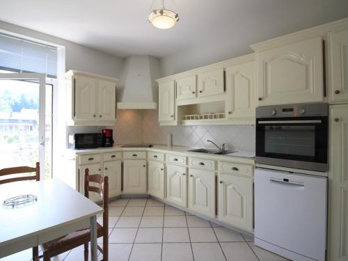 une cuisine avec des armoires blanches et une table et une salle à manger dans l'établissement Bel appartement 3*** La Bourboule, 6 pers, Wifi inclus - FR-1-608-250, à La Bourboule