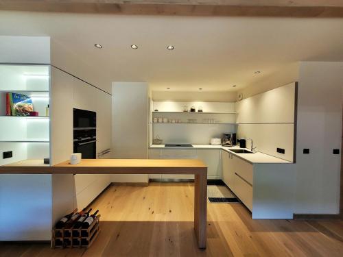 une cuisine avec des armoires blanches et une table en bois dans l'établissement Appartement prestigieux au centre avec cheminée, 6 pers, sauna, hammam, fitness, parking - FR-1-598-151, aux Gets