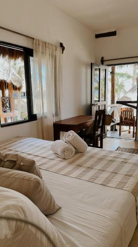 two beds in a room with a piano and a desk at La Conchita Tulum in Tulum