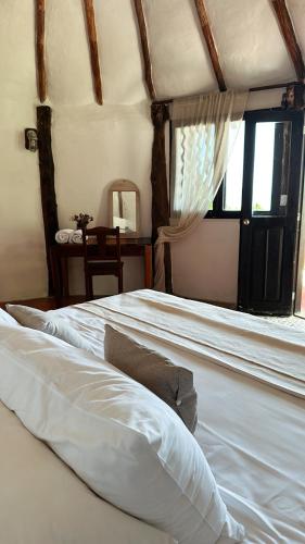 a bedroom with a large white bed with a window at La Conchita Tulum in Tulum
