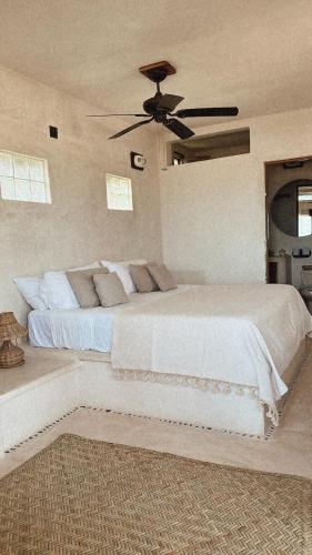 a bedroom with a white bed with a ceiling fan at La Conchita Tulum in Tulum
