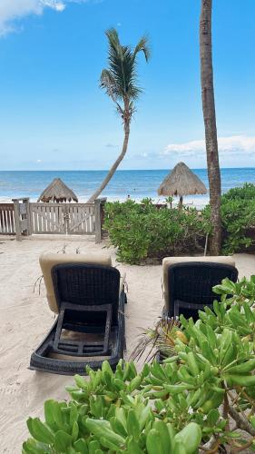 two chairs and umbrellas on a beach with the ocean at La Conchita Tulum in Tulum