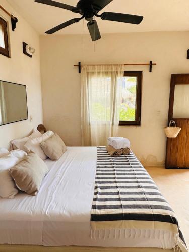 a bedroom with a large bed with a ceiling fan at La Conchita Tulum in Tulum