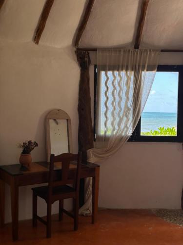 a room with a desk and a window with the ocean at La Conchita Tulum in Tulum
