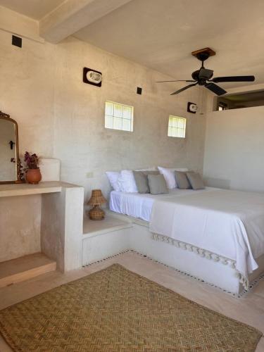 a bedroom with a white bed with a ceiling fan at La Conchita Tulum in Tulum