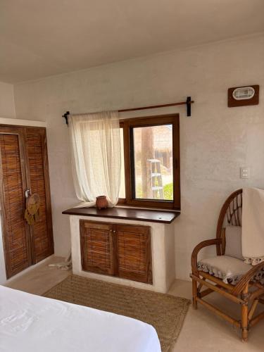 a bedroom with a bed and a window and a chair at La Conchita Tulum in Tulum