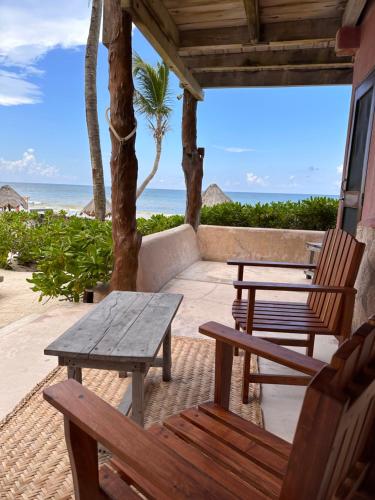 a patio with chairs and a table and the ocean at La Conchita Tulum in Tulum
