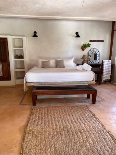 a bedroom with a bed with a table and a rug at La Conchita Tulum in Tulum