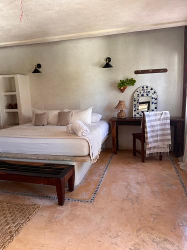 a bedroom with a bed and a table and a chair at La Conchita Tulum in Tulum
