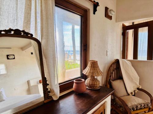 a bedroom with a mirror and a chair and a window at La Conchita Tulum in Tulum