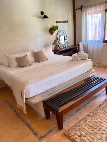 a bedroom with a large bed with a bench in it at La Conchita Tulum in Tulum
