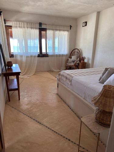 a bedroom with a bed and a table and windows at La Conchita Tulum in Tulum