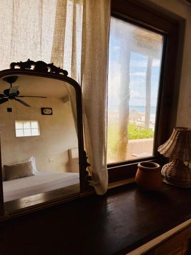 a mirror reflecting a bed in a room with a window at La Conchita Tulum in Tulum
