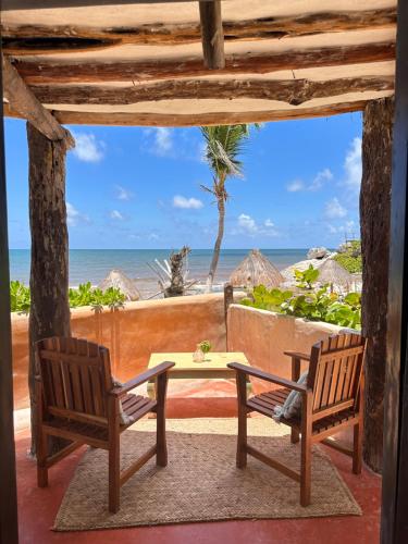a patio with two chairs and a table and the ocean at La Conchita Tulum in Tulum
