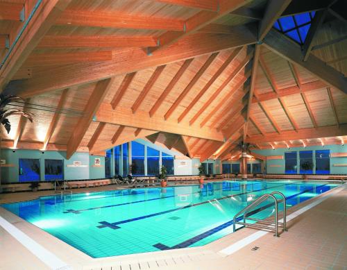 une grande piscine intérieure avec des plafonds en bois dans l'établissement Auberge du Lac-à-l'Eau-Claire, à Saint-Alexis-des-Monts
