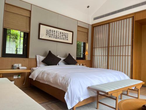 a bedroom with a large white bed and windows at 岷江书院人文度假酒店 in Chengdu