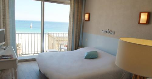 a bedroom with a bed with a view of the ocean at Hôtel des Druides in Quiberon