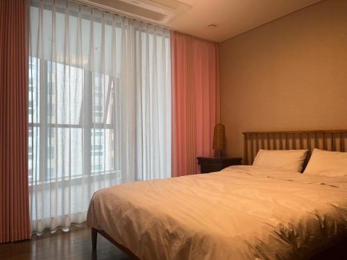 a bedroom with a bed and a large window at Haeundae Luxury House in Busan