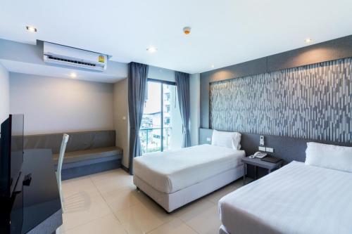 una camera d'albergo con due letti e una finestra di C Hotel Bangna a Bangkok