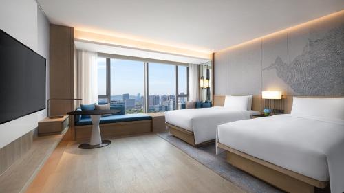 a hotel room with two beds and a television at Courtyard by Marriott Nanjing Jiangning in Nanjing