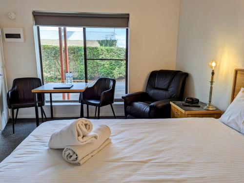 a hotel room with a bed with a towel on it at Arkana Motor Inn & Terrace Apartments in Mount Gambier