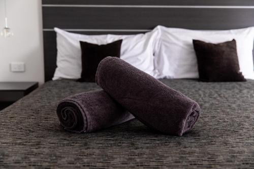 a couple of rolled up towels on a bed at Tea House Motor Inn in Bendigo