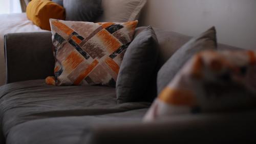 a brown couch with a pillow on it at El Hogar near UN Headquarters, Gigiri in Kiambu