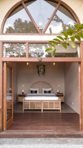 a bedroom with a bed and a large window at Les Rizieres Lombok - Tetebatu in Tetebatu