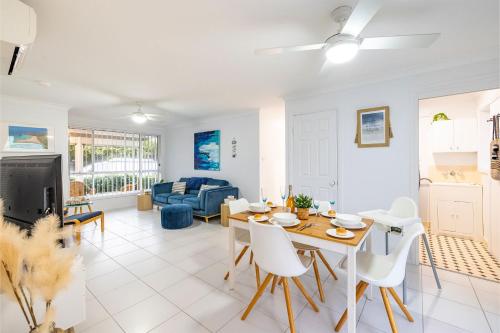 a living room with a table and chairs and a couch at Sapphire Sands 1 52 Boulder Bay Rd air con Wi Fi Cot and Highchair in Fingal Bay