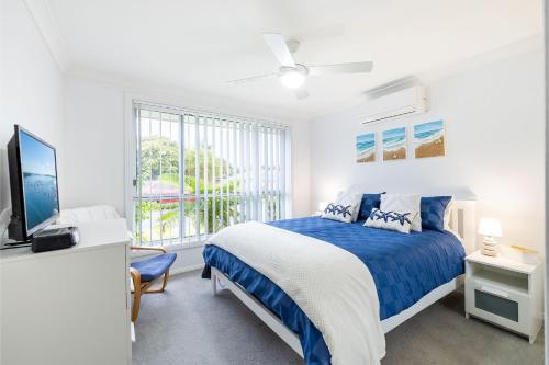 フィンガル・ベイにあるSapphire Sands 1 52 Boulder Bay Rd air con Wi Fi Cot and Highchairの白いベッドルーム(青いベッド1台、窓付)