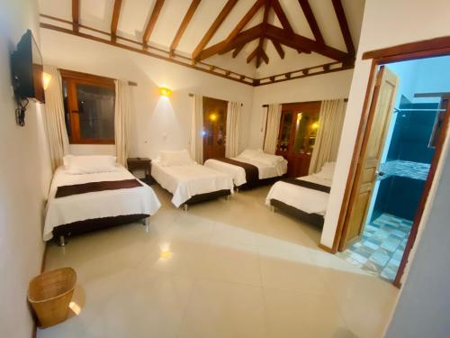 a bedroom with two beds and a large window at Hotel Oasis de la villa in Villa de Leyva