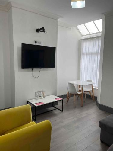 Complete 4 Bedroom House in Hanley-Free Parking في Hanley: غرفة معيشة مع أريكة صفراء وطاولة