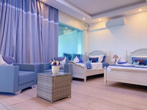 Habitación con 2 camas, sofá y mesa. en Crystal Beach Hotel, en Port Vila