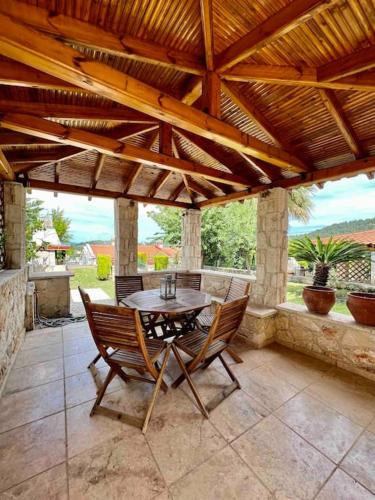 a patio with a table and chairs under a wooden roof at #ALS- Stone Maisonette in Paliouri in Paliouri