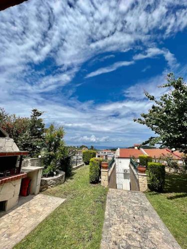 a blue sky with clouds above a yard with grass at #ALS- Stone Maisonette in Paliouri in Paliouri