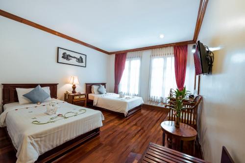 a hotel room with two beds and a window at The Suite By Royal Crown Hotel in Siem Reap