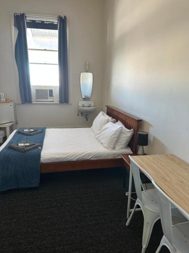 a bedroom with a bed and a table and a window at Cornwall Hotel in Moonta